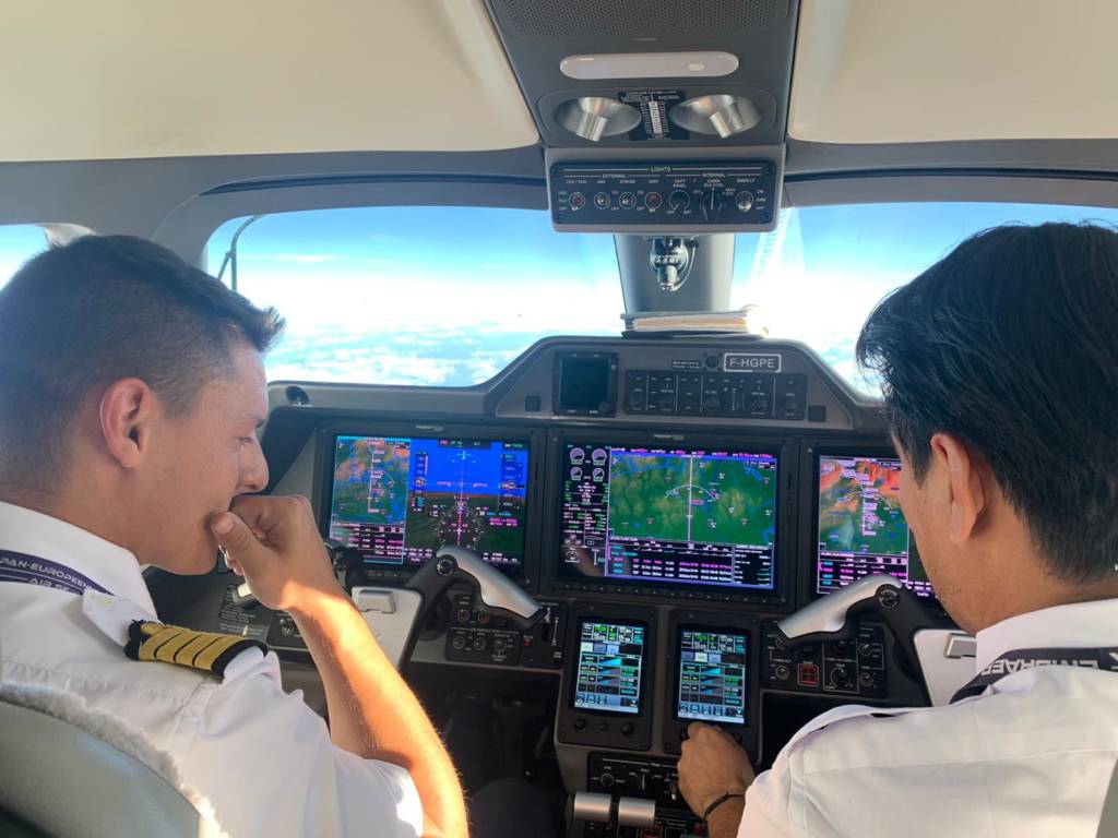 Deux pilotes aux commandes d'un Phenom 300 en vol, écrans du tableau de bord allumés