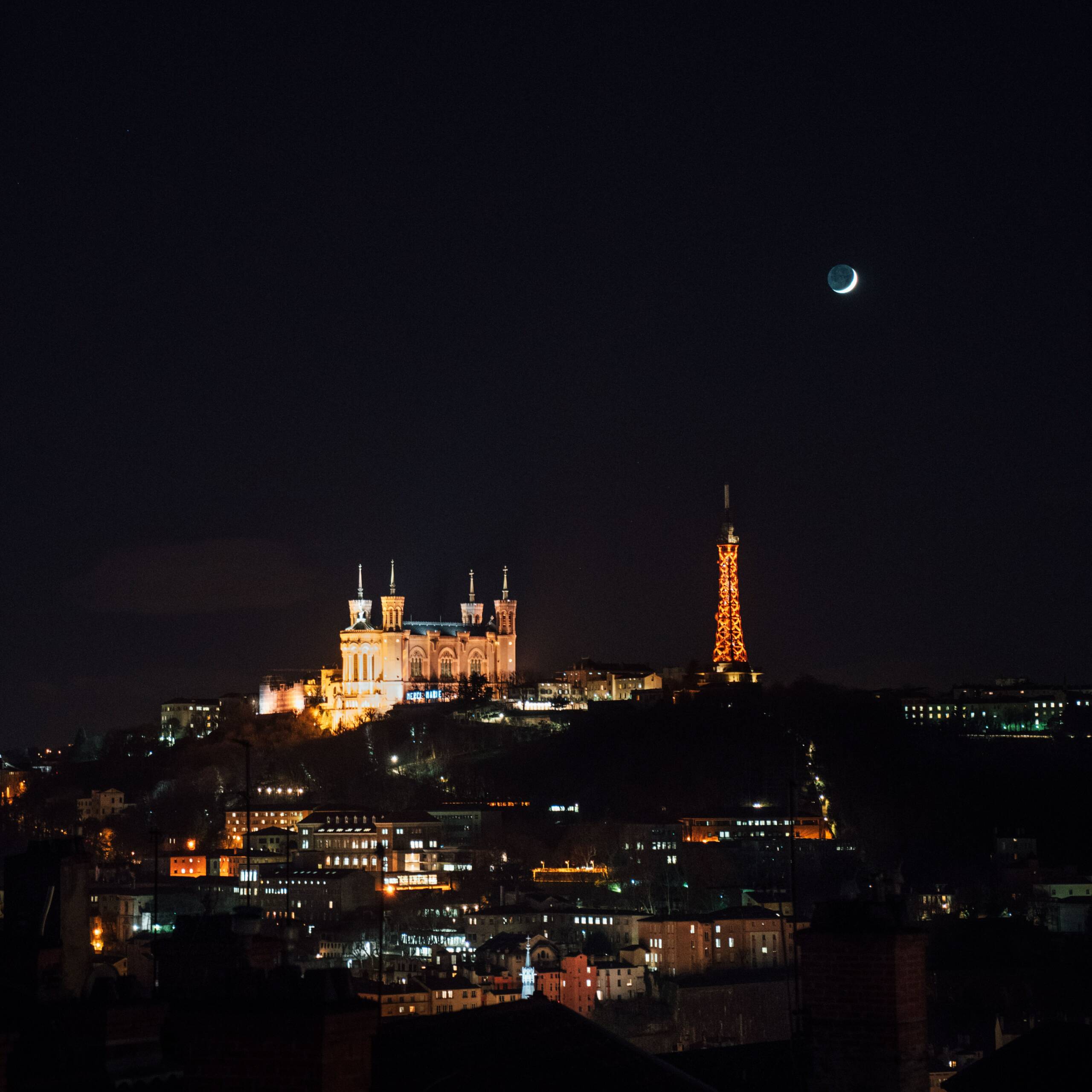 Image de Lyon le soir. On peut y apercevoir fourvière et une partie de la croix rousse. On voit la basilique Notre Date de Fourvièrer qui est illuminé ainsi que la tour eiffel de Lyon.