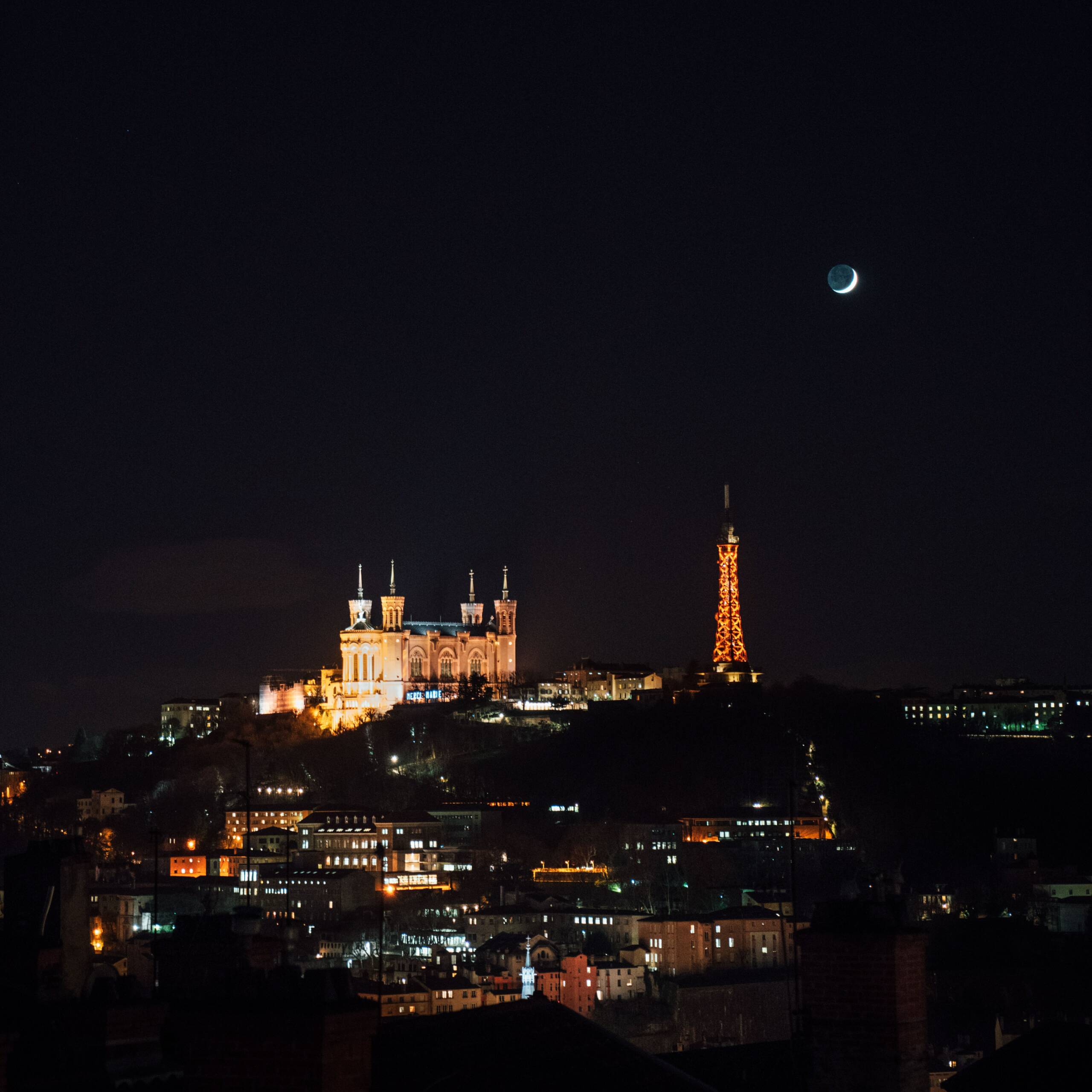 Fête des lumières à Lyon | Édition 2022 Image de Lyon le soir. On peut y apercevoir fourvière et une partie de la croix rousse. On voit la basilique Notre Date de Fourvièrer qui est illuminé ainsi que la tour eiffel de Lyon.