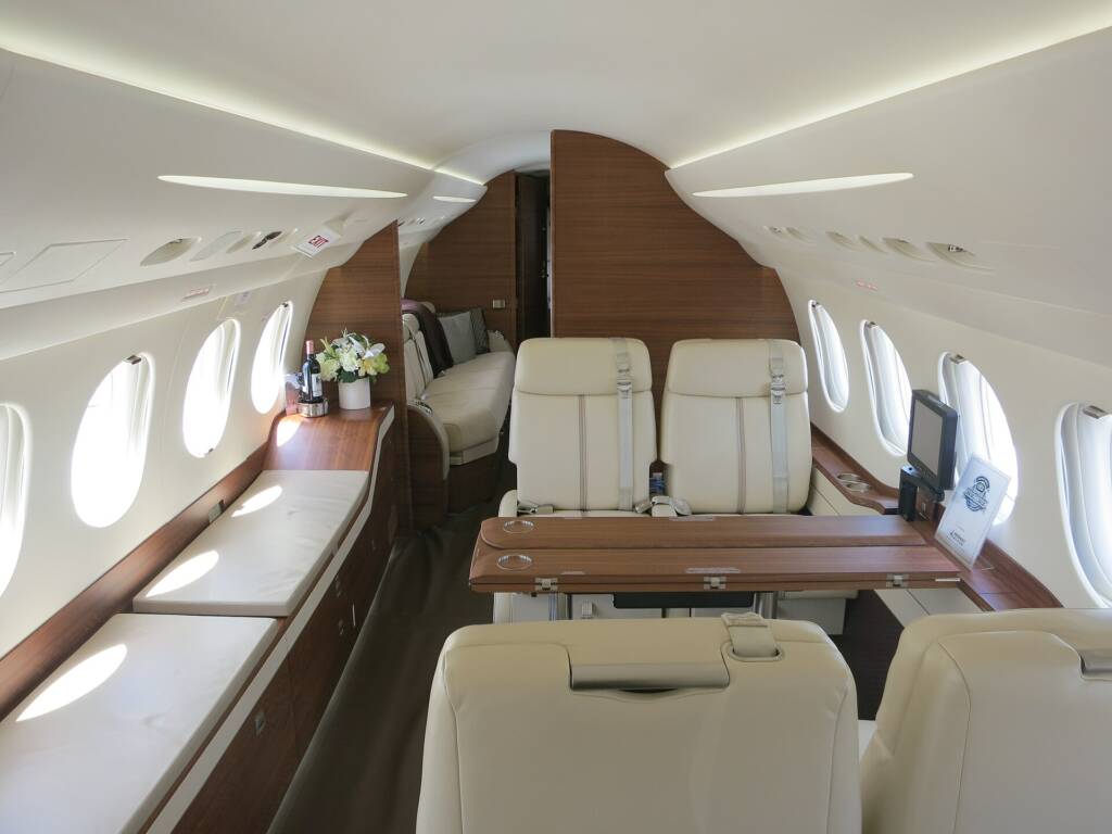Dassault Falcon 7X cabin, cream seats, wooden table and flowers