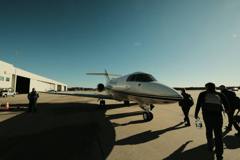 Passengers seen from behind walking to a private jet on the apron