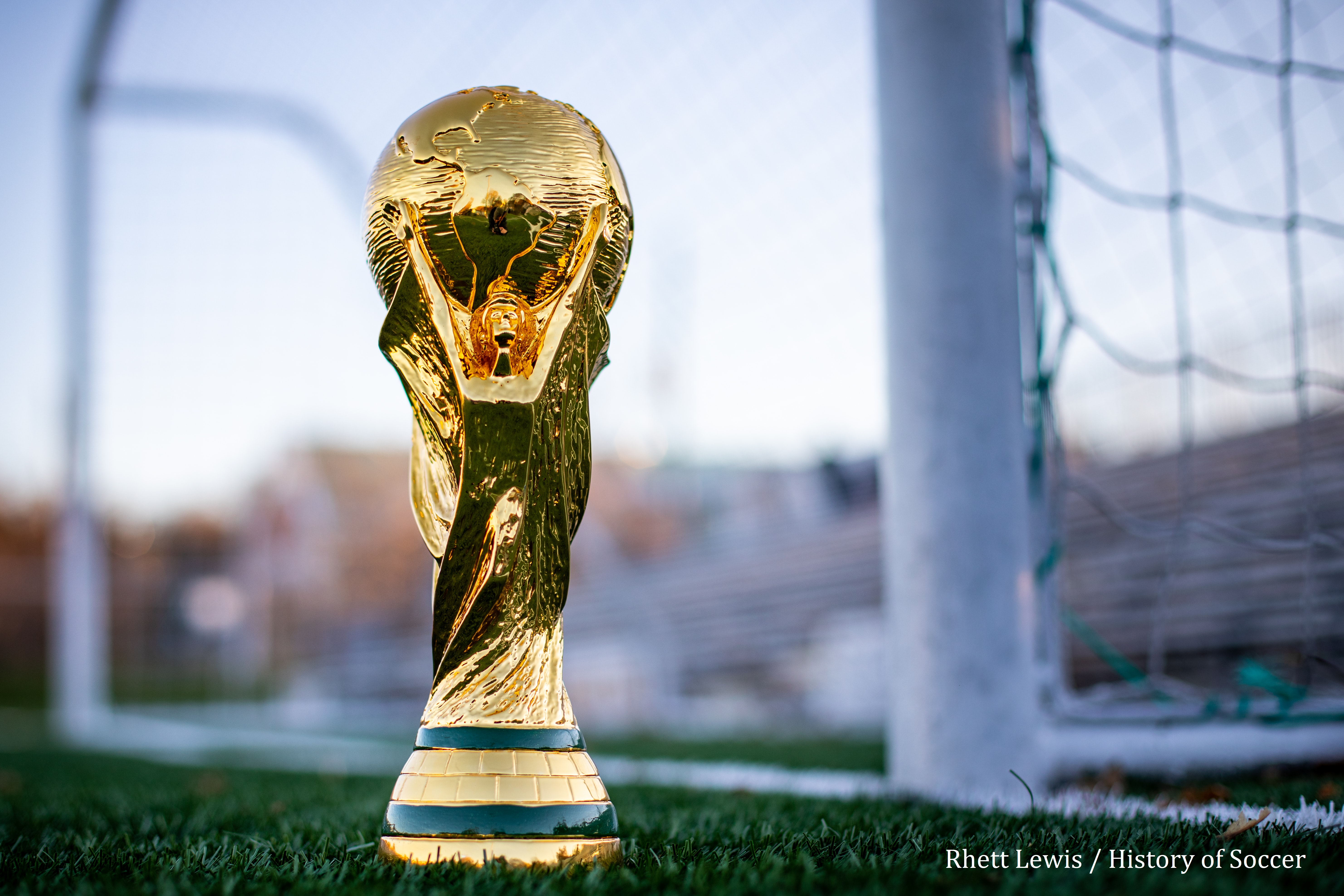 Photo By Rhett Lewis / Soccer History Coupe du monde posé sur gazon de stade de football, à l'arrière on peut voir la cage de but
